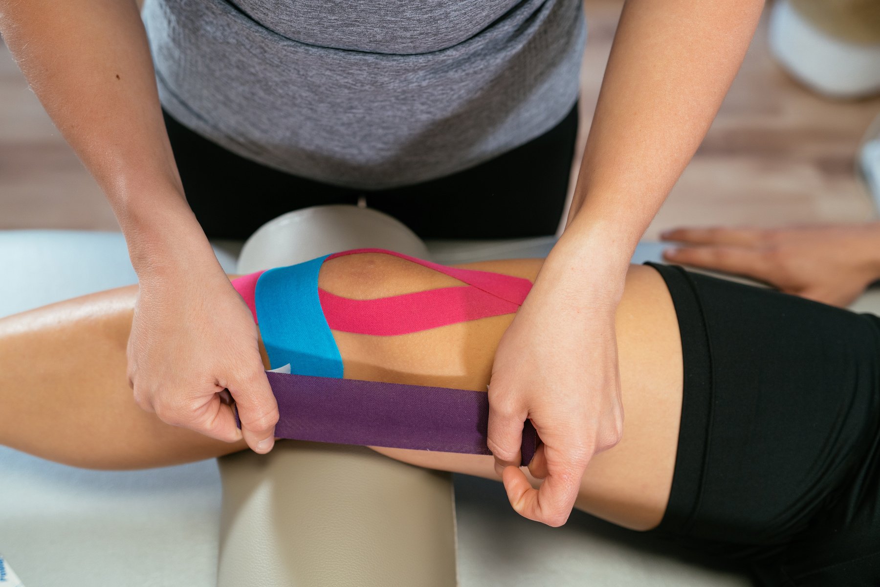 Physiotherapist Putting Kinesiology Tape to Strained Muscle